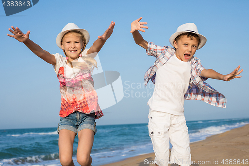 Image of Two happy little children playing on the beach at the day time.