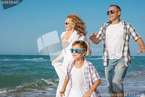 Image of Father mother and  son  playing on the beach at the day time.