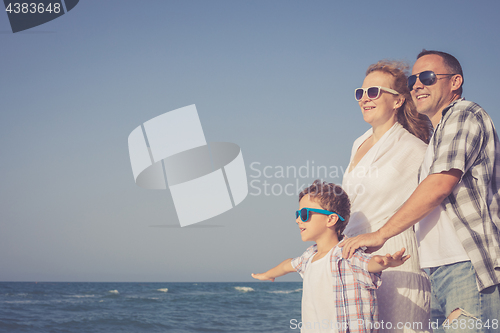 Image of Father mother and  son  playing on the beach at the day time.