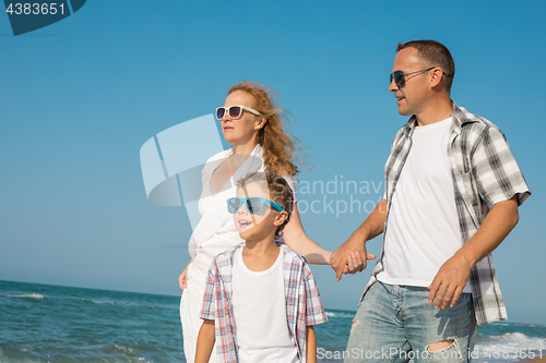 Image of Father mother and  son  playing on the beach at the day time.