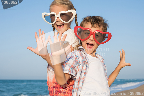 Image of Two happy little children playing on the beach at the day time.