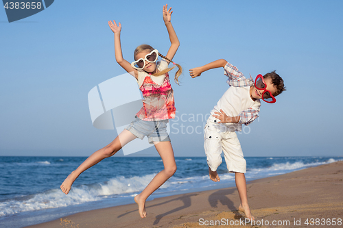 Image of Two happy little children playing on the beach at the day time.