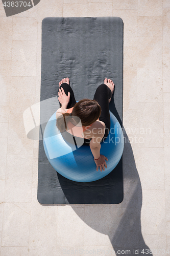 Image of woman doing exercise with pilates ball top view