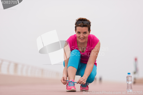 Image of Young woman tying shoelaces on sneakers