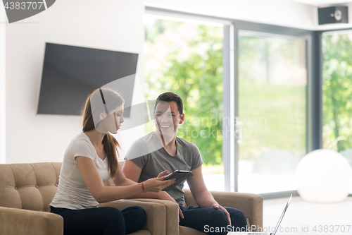 Image of couple relaxing at  home with tablet and laptop computers