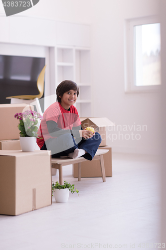 Image of boy sitting on the table with cardboard boxes around him