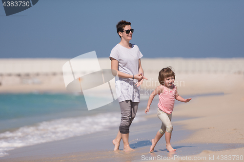 Image of mother and daughter running on the beach