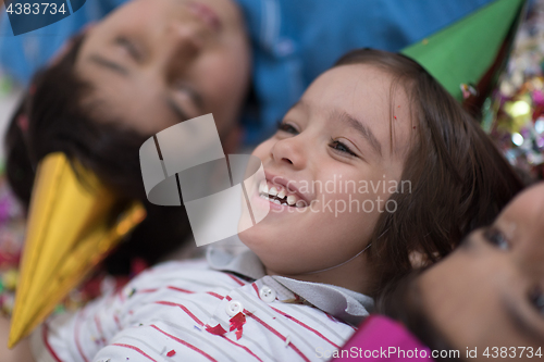 Image of kids  blowing confetti while lying on the floor