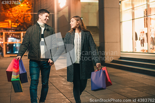 Image of The happy couple with shopping bags enjoying night at city background