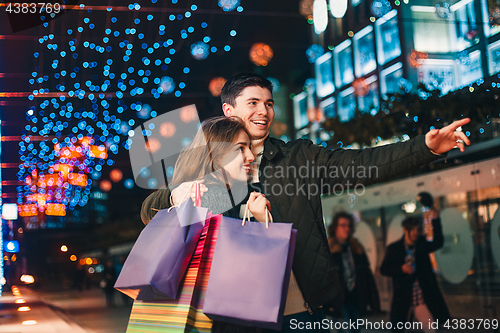 Image of The happy couple with shopping bags enjoying night at city background