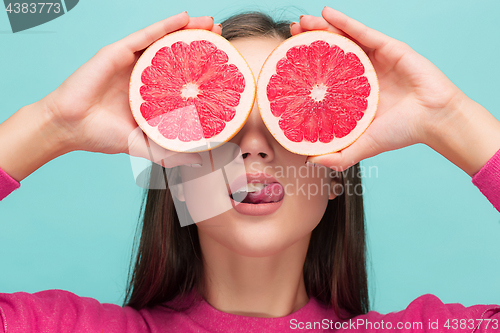 Image of Pretty woman with delicious grapefruit in her arms.