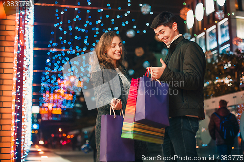 Image of The happy couple with shopping bags enjoying night at city background