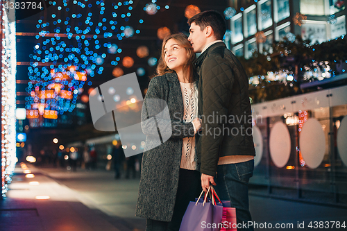 Image of The happy couple with shopping bags enjoying night at city background