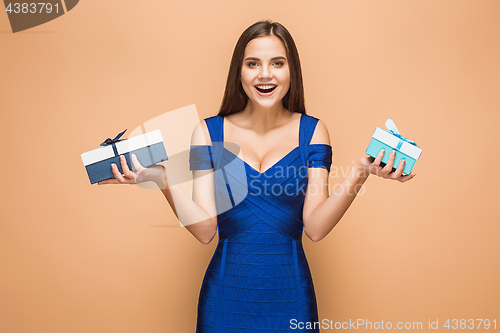 Image of Portrait of happy young woman holding a gifts on brown