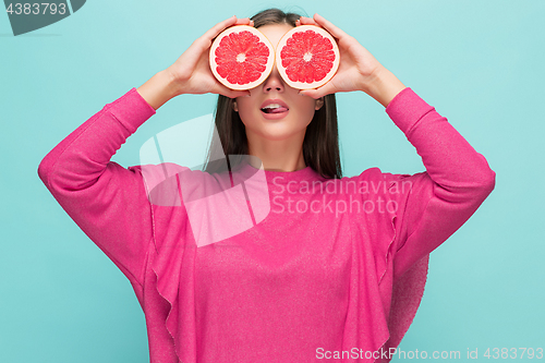 Image of Pretty woman with delicious grapefruit in her arms.