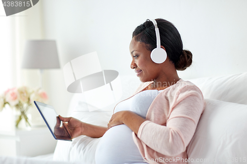 Image of pregnant woman in headphones with tablet pc