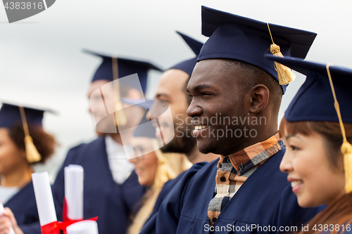 Image of happy students in mortar boards with diplomas