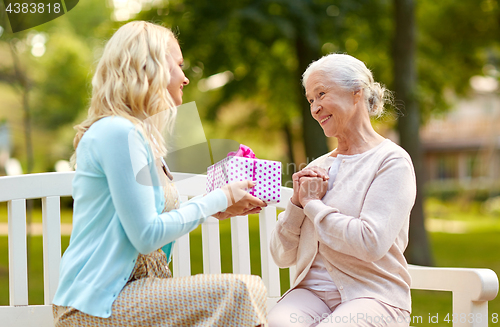 Image of daughter giving present to senior mother at park