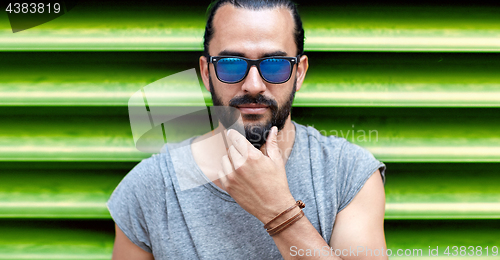 Image of close up of man in sunglasses touching beard