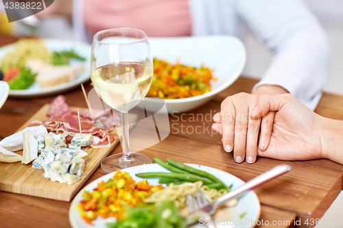 Image of hands of people at table praying before meal