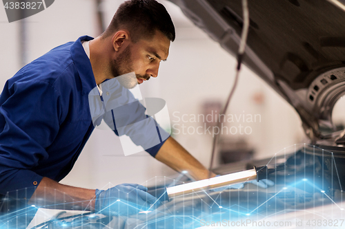 Image of mechanic man with lamp repairing car at workshop