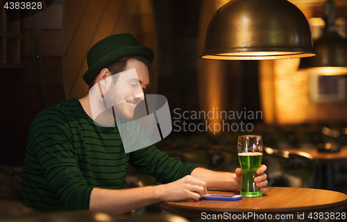 Image of man with smartphone and green beer at bar or pub