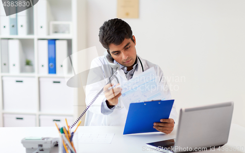 Image of doctor with clipboard calling on phone at clinic