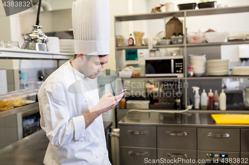 Image of chef cook with smartphone at restaurant kitchen