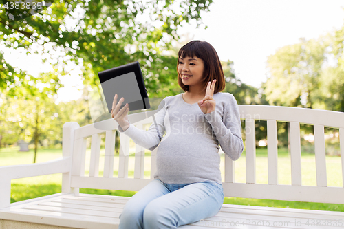 Image of happy pregnant asian woman with tablet pc at park