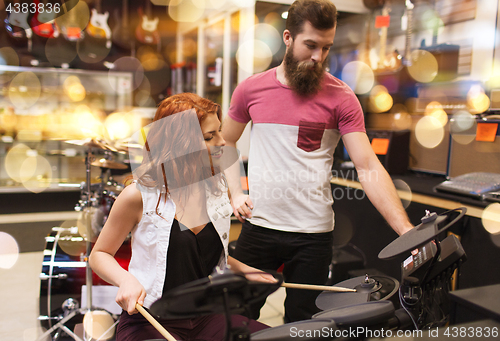 Image of couple of musicians with drum kit at music store