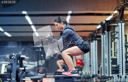 Image of woman doing squats on platform in gym