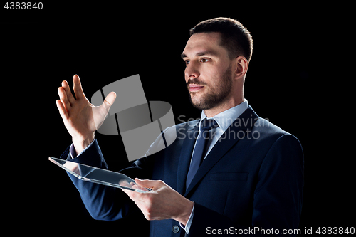 Image of businessman in suit working with transparent tablet pc