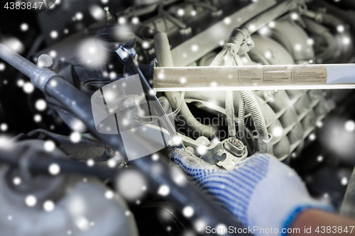 Image of mechanic hand with wrench and lamp repairing car