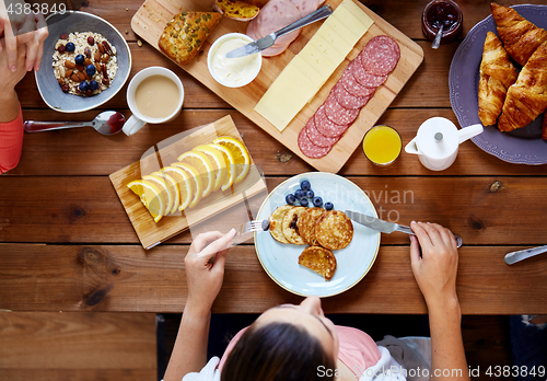 Image of woman with food on table eating pancakes