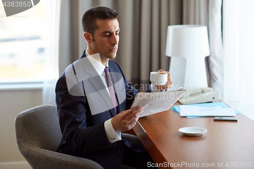 Image of businessman reading newspaper and drinking coffee