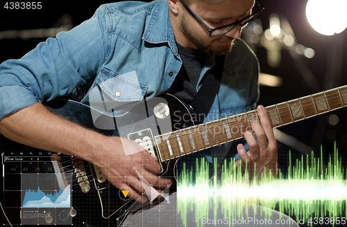 Image of close up of musician playing guitar at studio