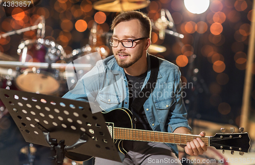 Image of musician playing guitar at studio over lights