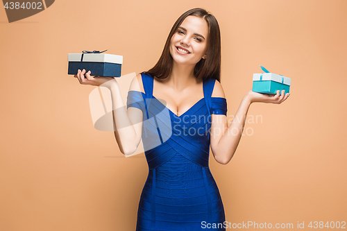 Image of Portrait of happy young woman holding a gifts on brown