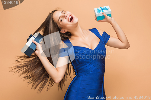 Image of Portrait of happy young woman holding a gifts on brown