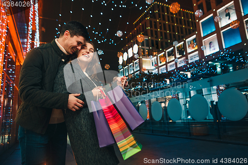 Image of The happy couple with shopping bags enjoying night at city background