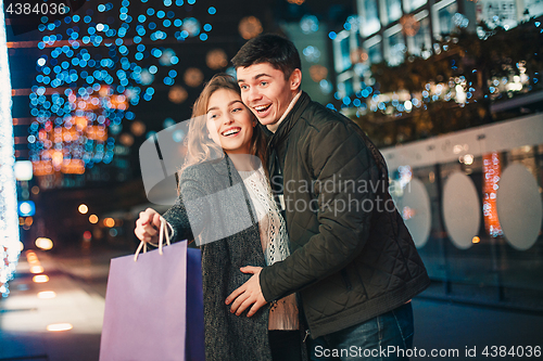 Image of The happy couple with shopping bags enjoying night at city background