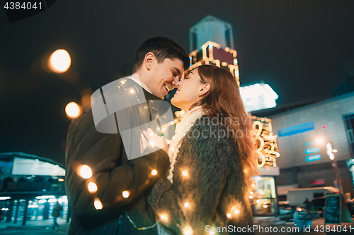 Image of Young couple kissing and hugging outdoor in night street at christmas time