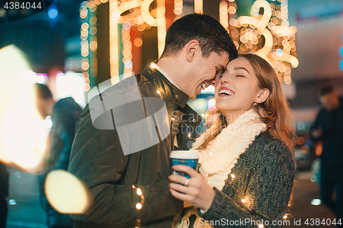 Image of Young couple kissing and hugging outdoor in night street at christmas time