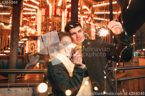 Image of Young couple kissing and hugging outdoor in night street at christmas time