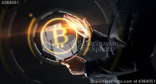 Image of businessman with tablet pc and bitcoin hologram