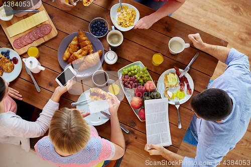 Image of people with smartphones eating food at table