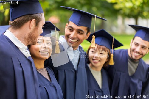 Image of happy students or bachelors in mortar boards