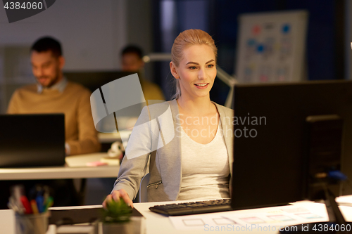 Image of businesswoman at computer working at night office