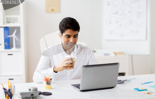 Image of businessman with laptop drinking coffee at office