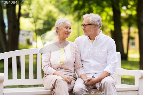 Image of happy senior couple sitting on bench at park